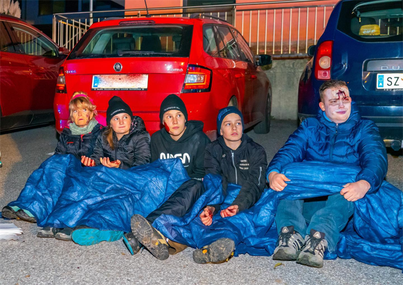 Eine Gruppe von Menschen sitzt auf dem Boden vor Autos